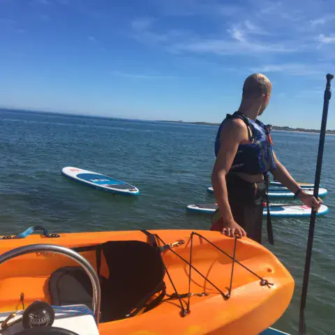 Moniteur sur le bateau d'assistance avec des planches de paddle