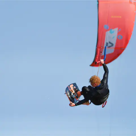 Kitesurfeur en l'air sous son aile rouge