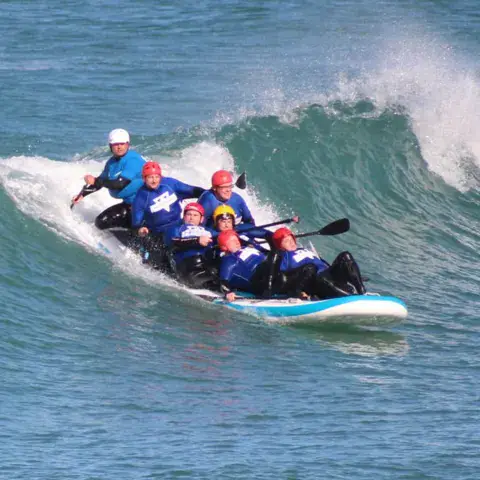 Équipe sur un grand paddle dans une vague