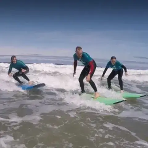 Trois surfeurs glissant sur la mousse de la vague