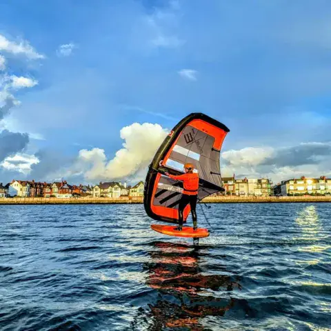 Wingfoil au coucher du soleil devant le front de mer
