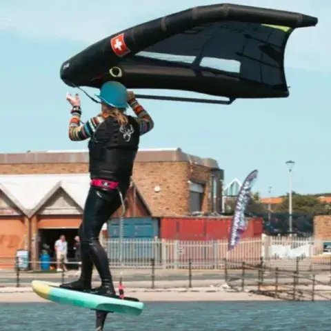 Rider tenant son aile devant la planche près du front de mer