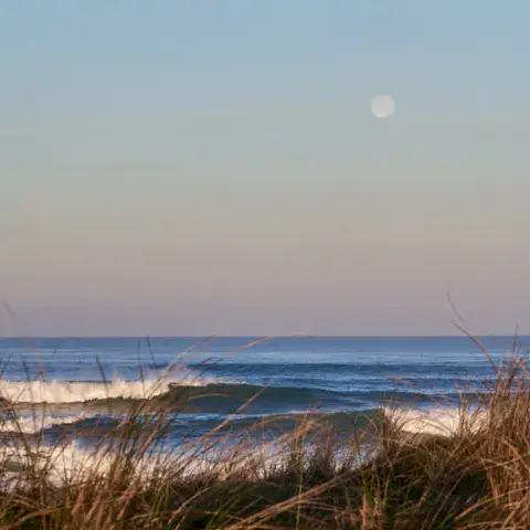 Vagues au lever de la lune derrière les dunes
