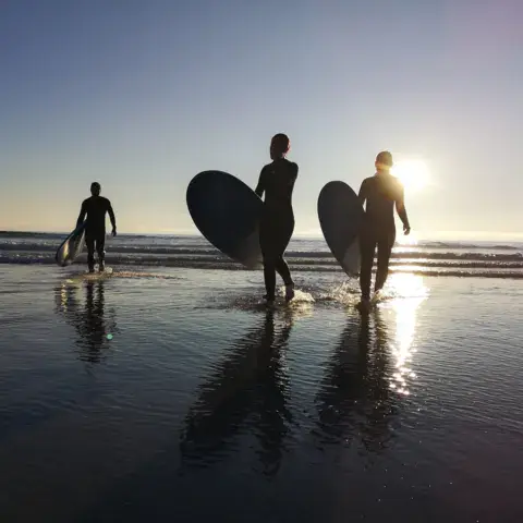 Surfeurs avec leurs planches au coucher du soleil sur la plage