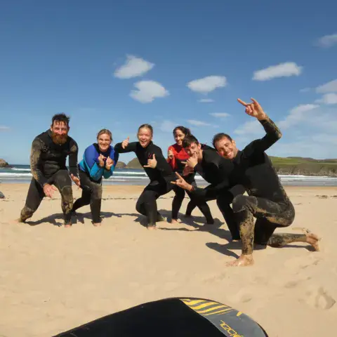 Groupe de surfeurs en combinaison posant sur la plage