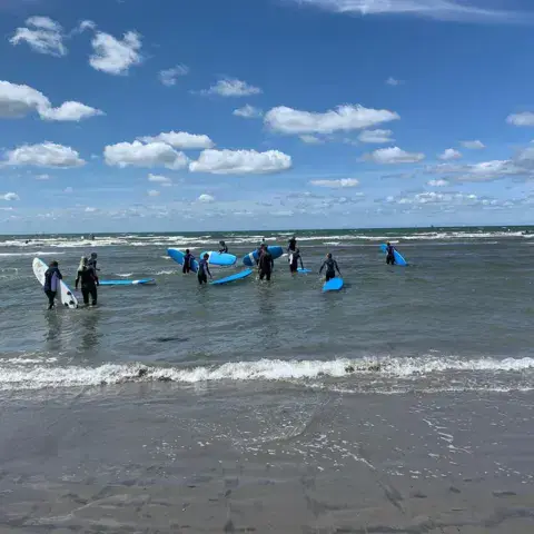 Groupe de débutants avec des planches de surf dans l'eau