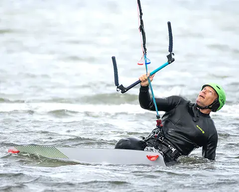 Kitesurfeur casqué avec sa barre, à fleur d'eau