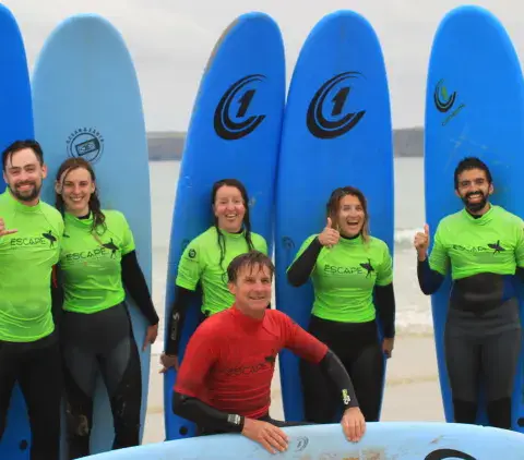 Groupe d'élèves et moniteurs posant avec des planches sur la plage