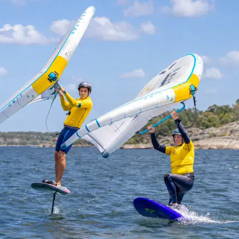 Deux élèves en wing foil le long d'une côte rocheuse