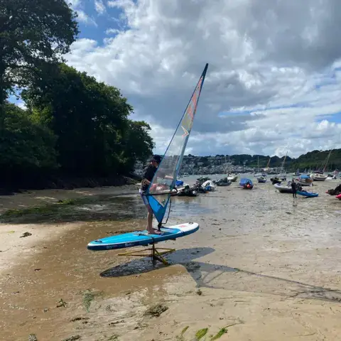 Windsurfeur qui s'entraîne sur une plage de sable à marée basse