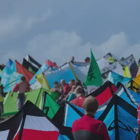 Kites posés sur la plage et riders rassemblés