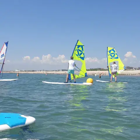 Cours de windsurf en groupe, voiles jaune et verte