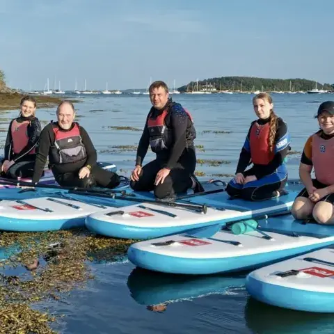 Un groupe à genoux sur des paddles, en eau peu profonde