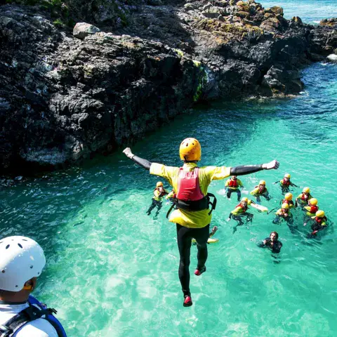 Saut dans une eau turquoise pendant une sortie de coasteering
