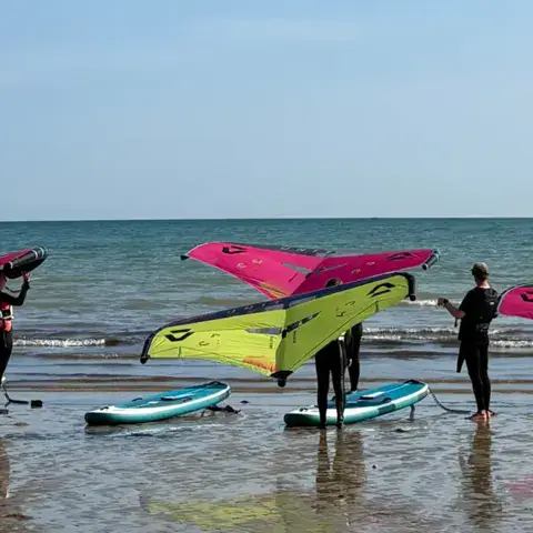 Groupe d'élèves avec leurs ailes de wing au bord de l'eau