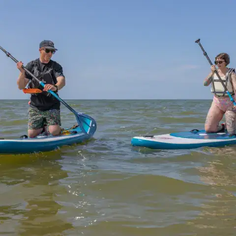 Deux personnes à genoux sur des paddles, pagaie en main