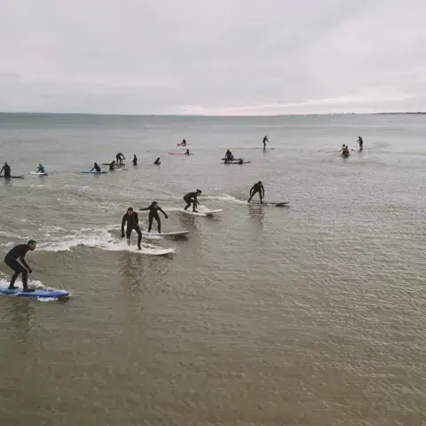 Groupe de surfeurs à l'eau pendant un cours