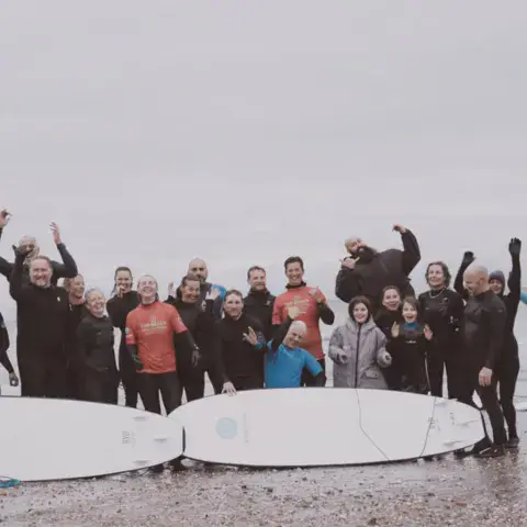 Grand groupe de surfeurs en combinaison avec des planches