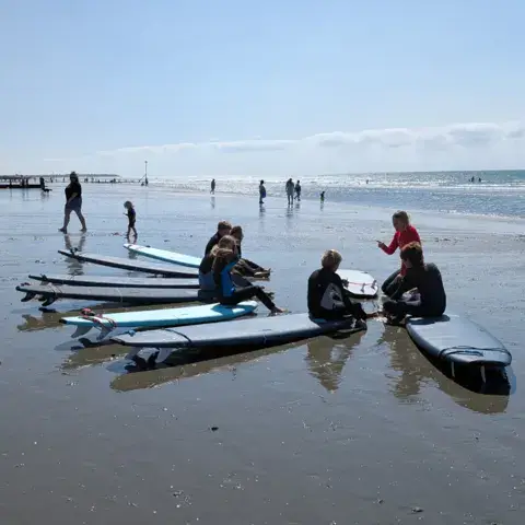 Élèves et planches de surf alignées sur la plage