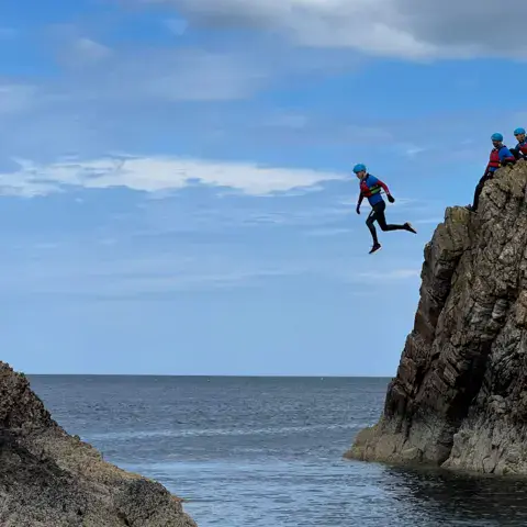 Saut dans l'eau depuis un rocher lors d'une sortie de coasteering