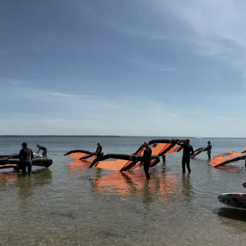 Élèves de wing foil avec leurs ailes dans la baie