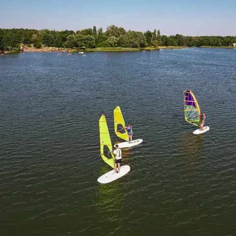 Trois véliplanchistes sur le lac, vus du ciel