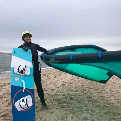 Kitesurfeur avec sa planche et son aile sur la plage