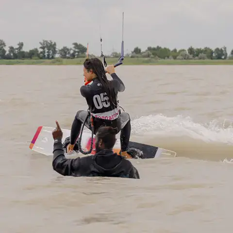 Un kitesurfeur sur l'eau, avec une autre personne près de lui, sur le lac de Neusiedl