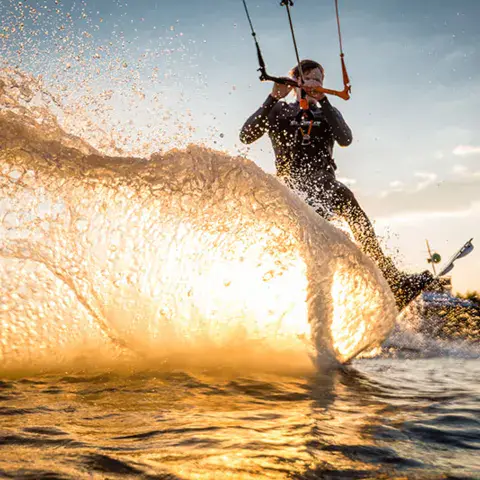 Un kitesurfeur qui glisse sur l'eau en soulevant des gerbes d'eau