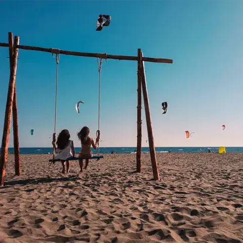 Plage de sable avec des ailes dans le ciel et une balançoire