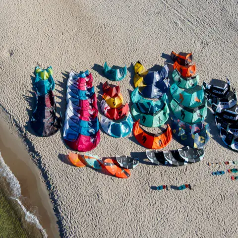 Ailes de kitesurf étalées sur la plage, vues du ciel