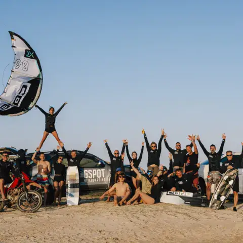 Groupe de kitesurfeurs devant une aile gonflée