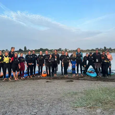 Groupe d'élèves en combinaison sur la plage après un cours