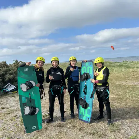 Groupe de kitesurfeurs casqués avec leurs planches au bord de la mer