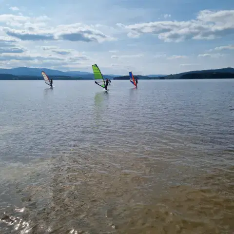 Des planchistes au large sur le lac de Lipno
