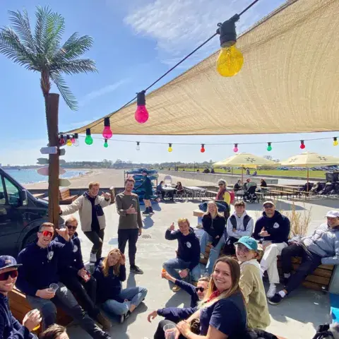 Groupe attablé sur une terrasse de plage décorée de guirlandes