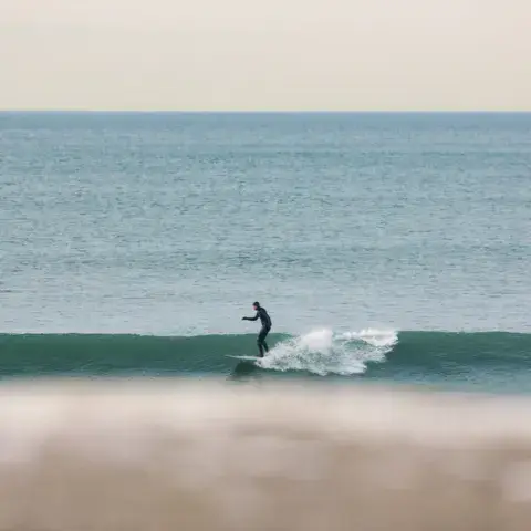 Surfeur sur une vague au large d'une plage
