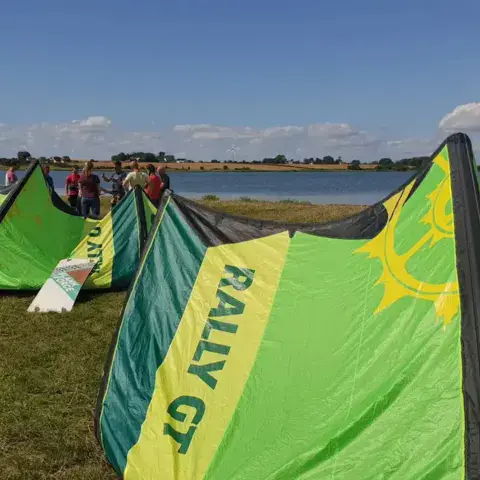 Ailes de kitesurf déployées sur l'herbe au bord de l'eau