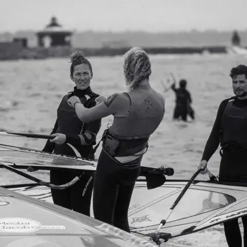 Moniteurs de windsurf et élèves au bord de l'eau, en noir et blanc