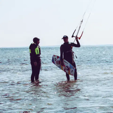 Moniteur et élève dans l'eau peu profonde avec une planche de kitesurf