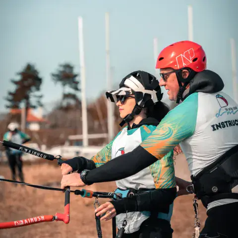 Moniteur et élève tenant ensemble la barre d'une aile de kitesurf