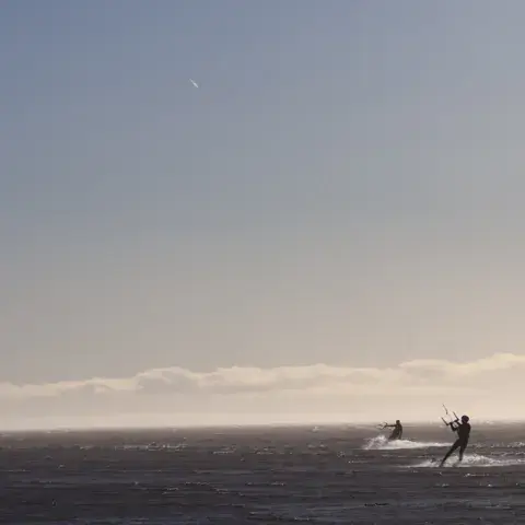 Un kitesurfeur sous son aile, à contre-jour