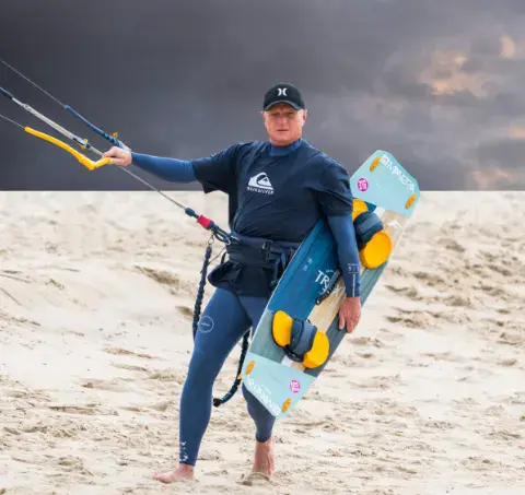 Kitesurfeur avec sa planche et ses lignes sur la plage