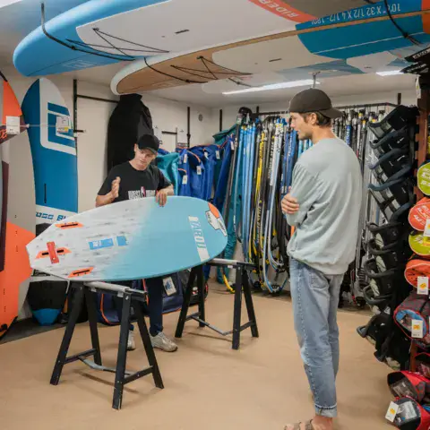 Intérieur du magasin avec planches de wing, de windsurf et accessoires