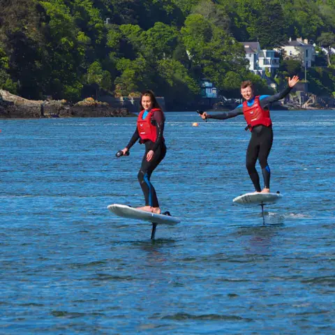 Deux élèves sur des e-foils, en gilet de sécurité