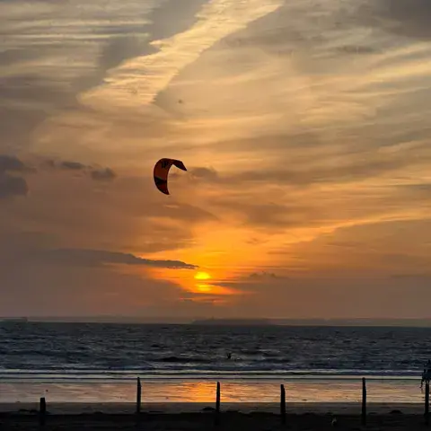 Kite dans le ciel au coucher du soleil, au bord de la mer