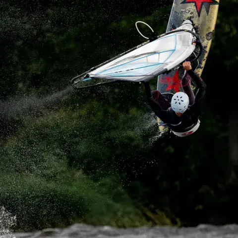 Windsurfeur en saut au bord d'un plan d'eau