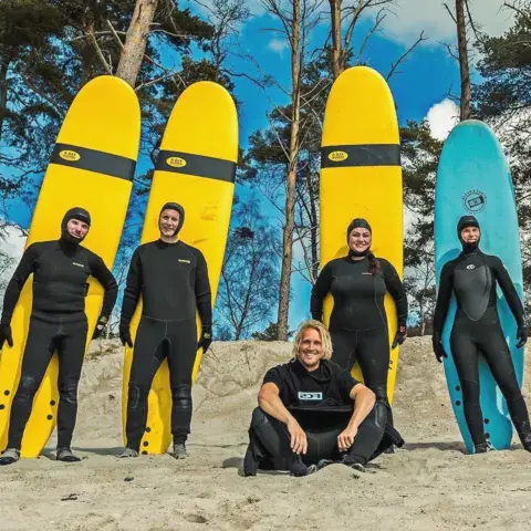 Groupe en combinaison avec des planches de surf sur la plage