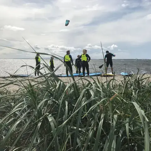 Groupe avec des planches de paddle sur la plage