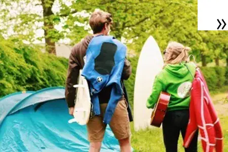 Deux personnes avec planches de surf près d'une tente